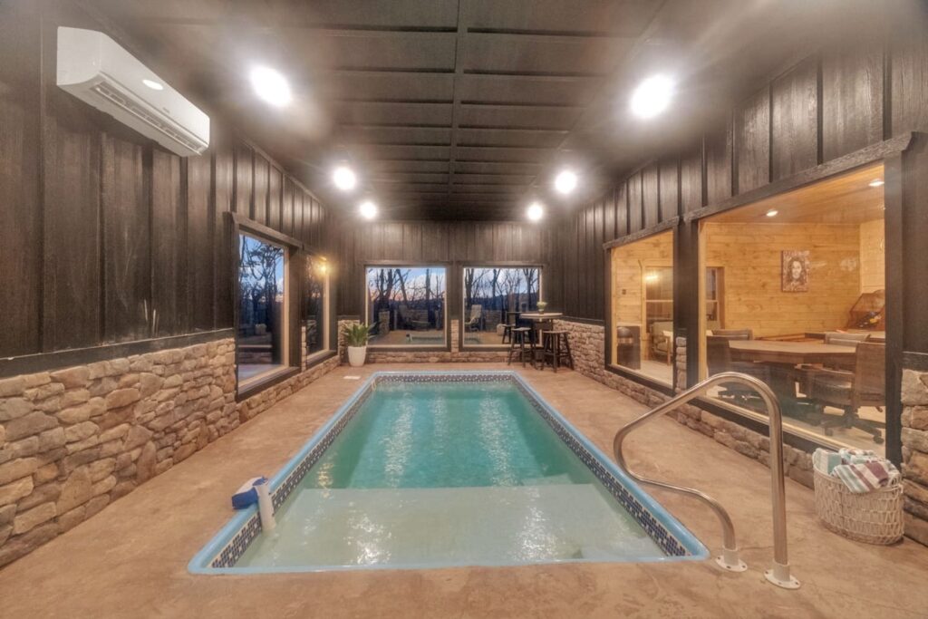 Indoor pool room with outdoor access to hot tub and walkway to fire pit